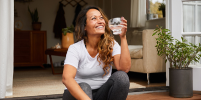 woman sitting on steps smiling while holding a glass of water