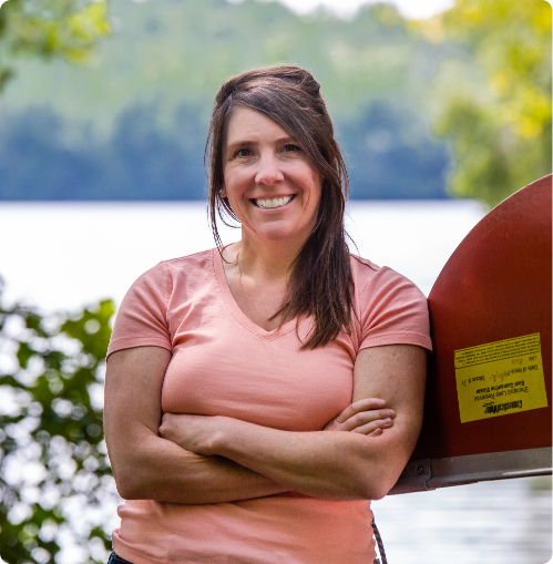 smiling woman leaning against a upside down canoe