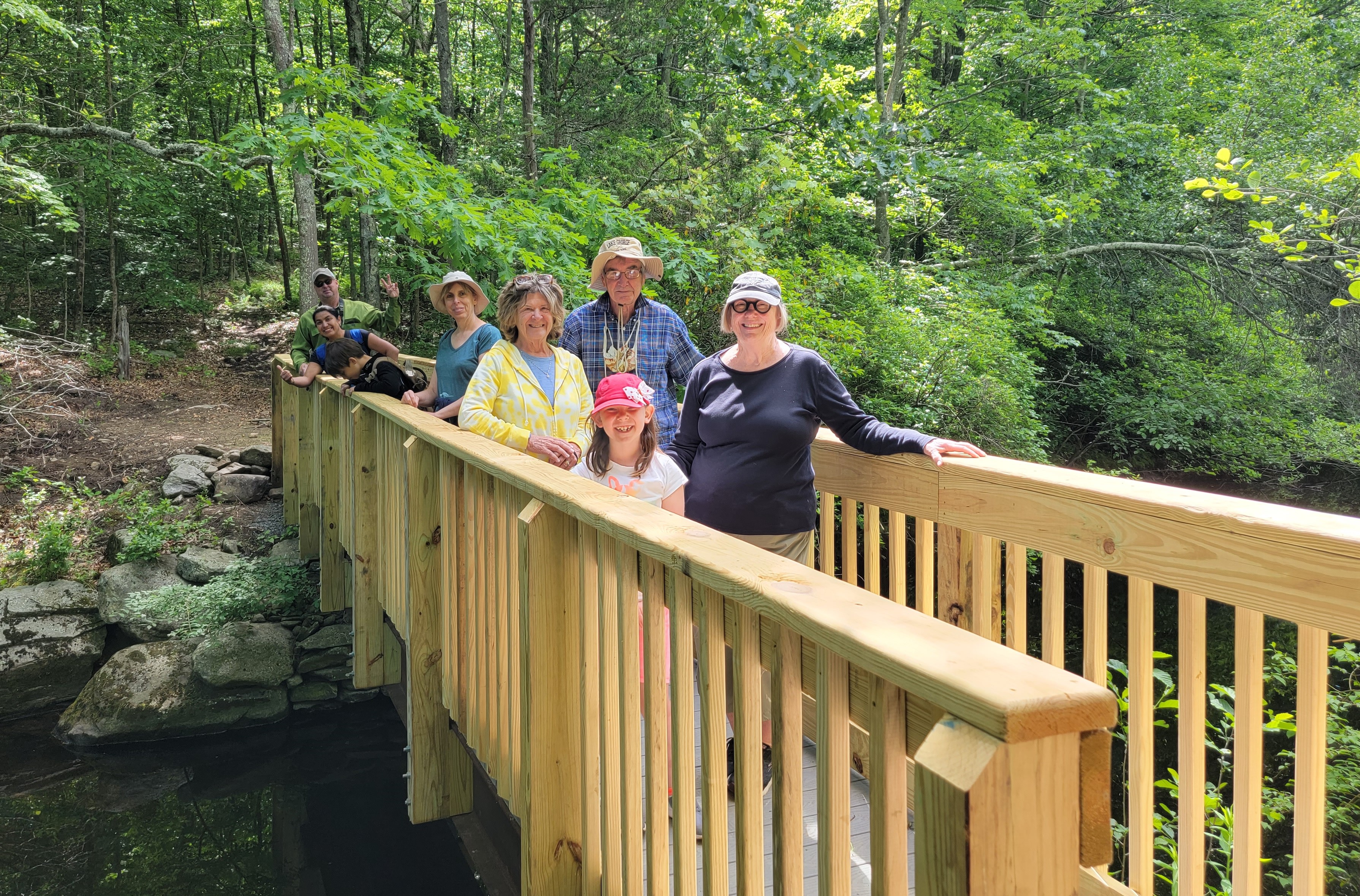 a group of people standing on a bridge during a hike of the Killingworth trails