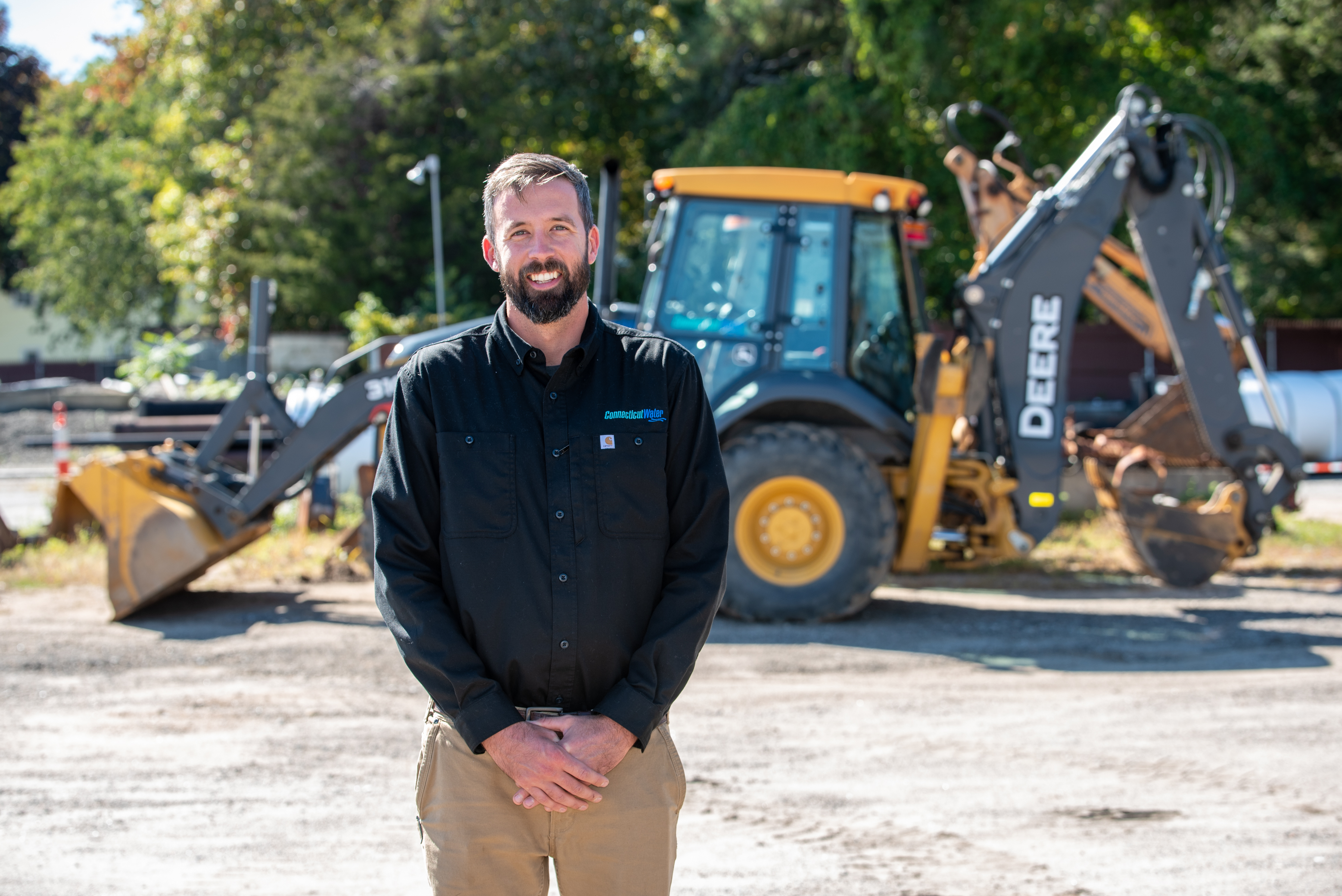 CT Water employee standing in front of a backhoe